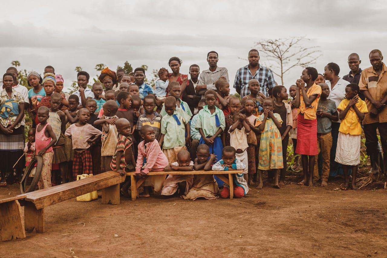 A diverse community gathering in Masindi, Uganda, featuring adults and children together outdoors.